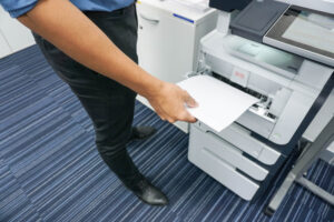 A person is holding paper in front of the printer.