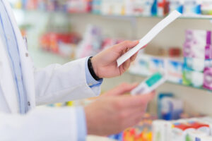 A person holding papers in their hands while standing at the pharmacy.